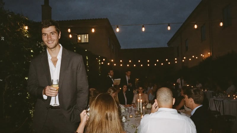 man in a charcoal suit holding champagne at an evening wedding reception as a dressed-up dating photo example