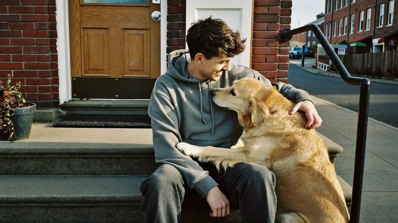 man laughing on brick front steps while his golden retriever nuzzles him as a pet dating photo example