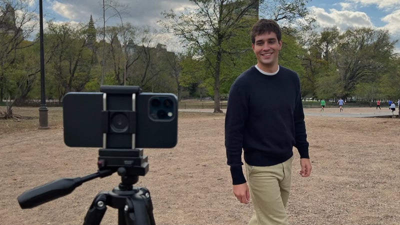man walking back toward a phone on a small tripod in a city park, framed on the rule of thirds line for a self-timer dating photo